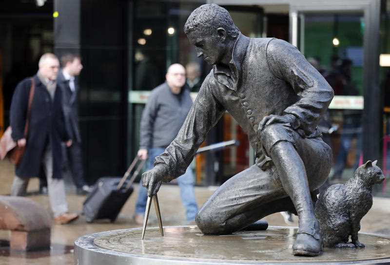 Pedestrians pass by the Matthew Flinders statue at Euston Railway station in London