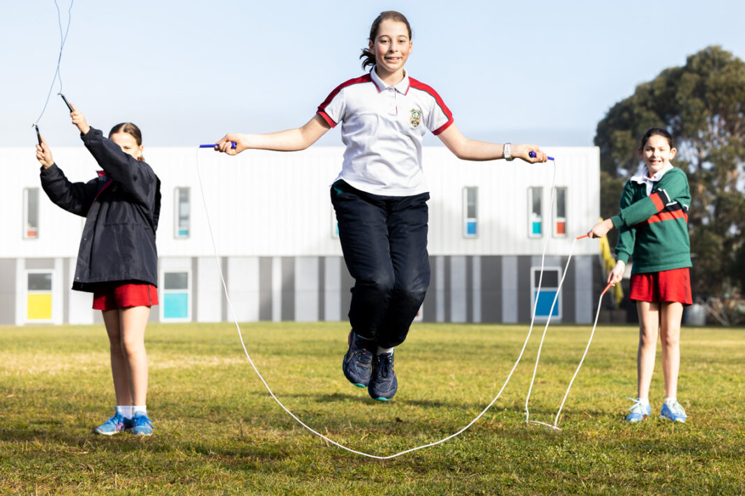 three girls doing jump rope on an oval