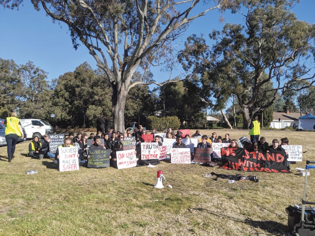 people sitting on grass holding up signs