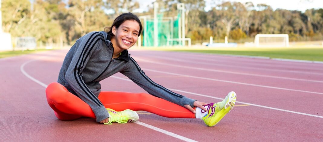 young female stretching on athletic track
