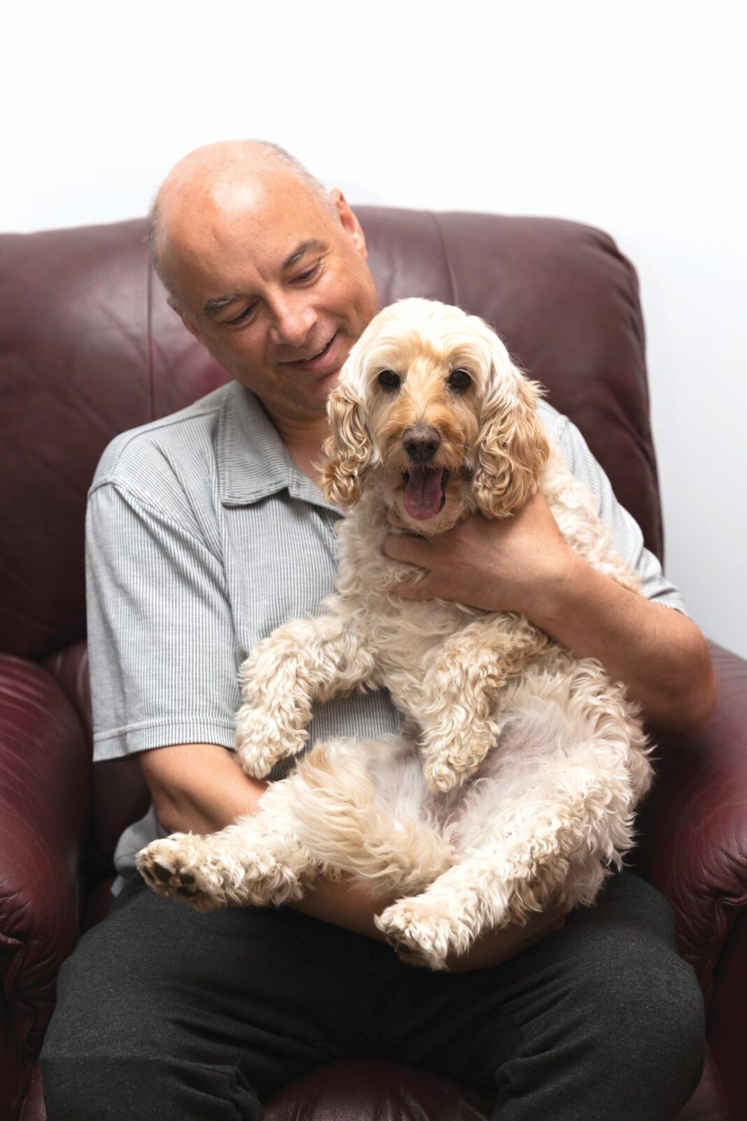 man on chair with dog on his lap