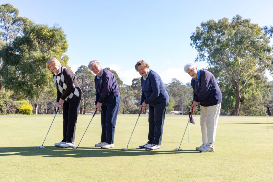 four elderly women playing golf
