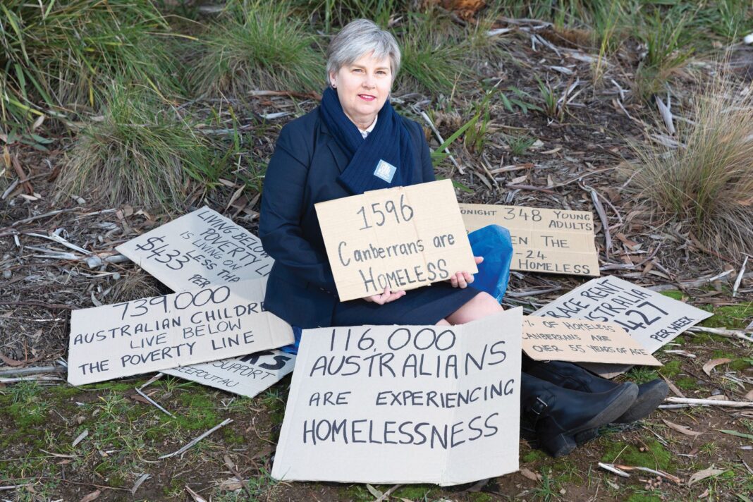 woman sitting on ground holding sign