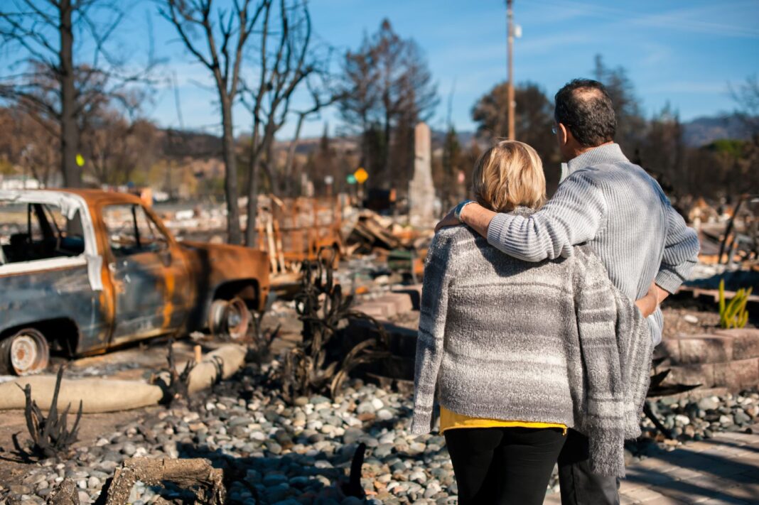 couple looking at rubble of home that was destroyed by bushfire