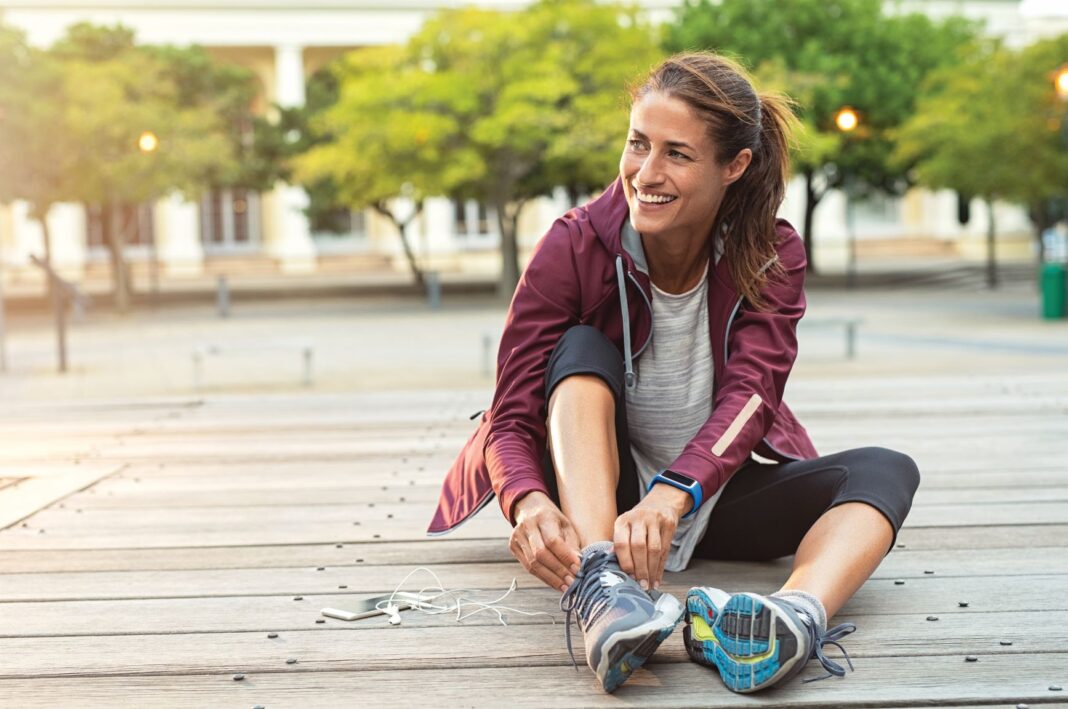 woman putting on running shoes smiling