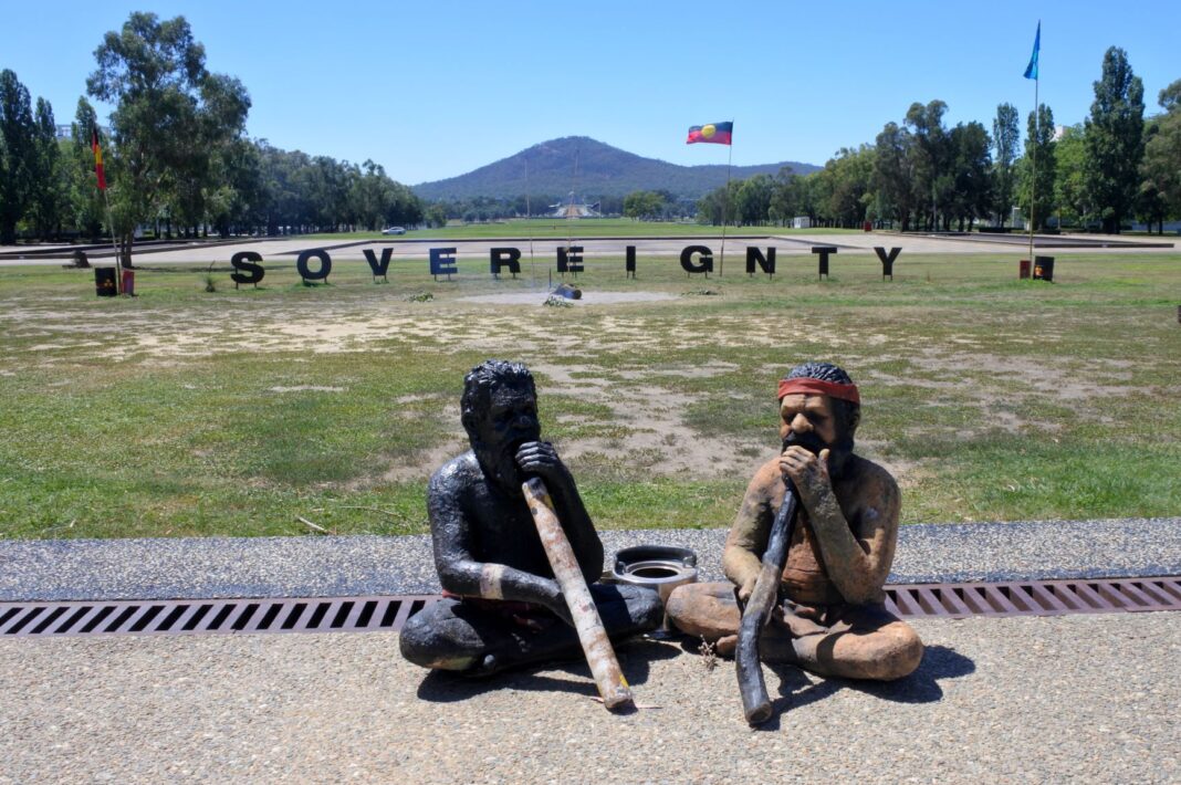 two statues with aboriginal flag in background