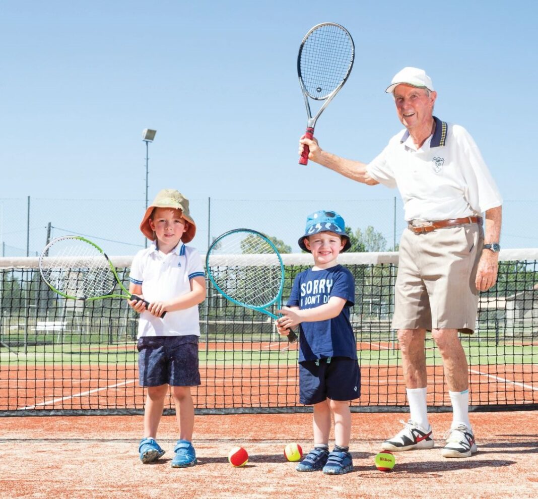 elderly man with two kids holding tennis rackets
