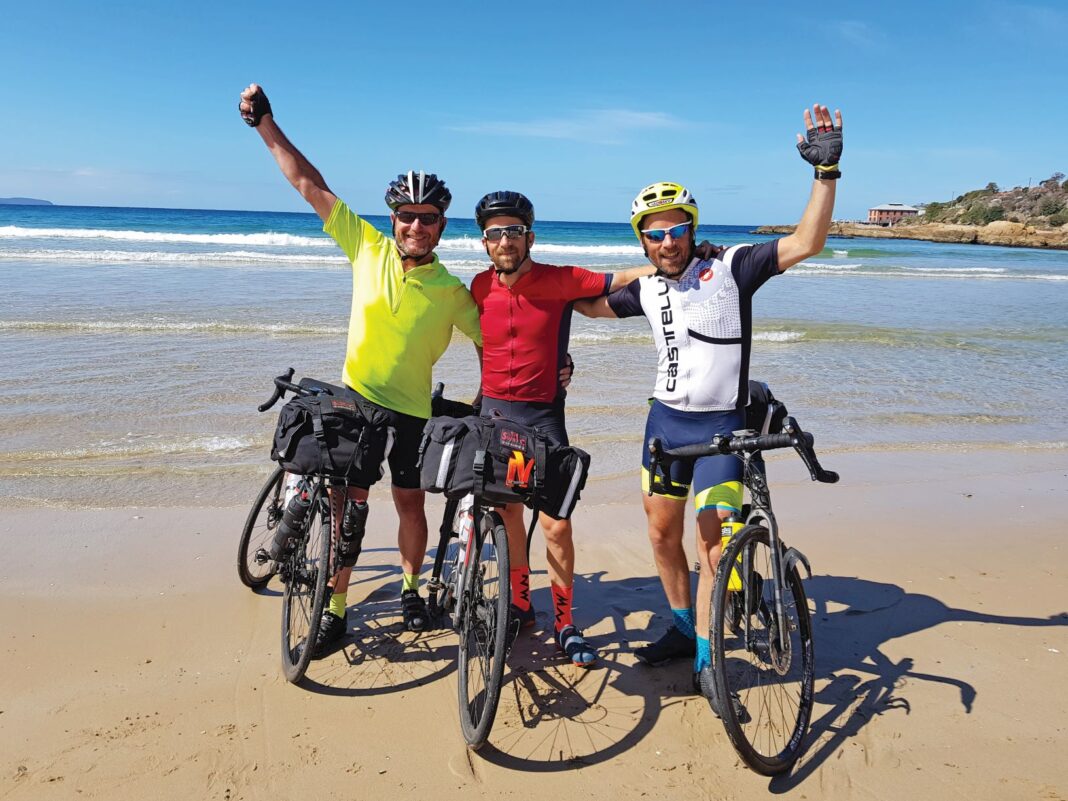 three men on bikes on the beach