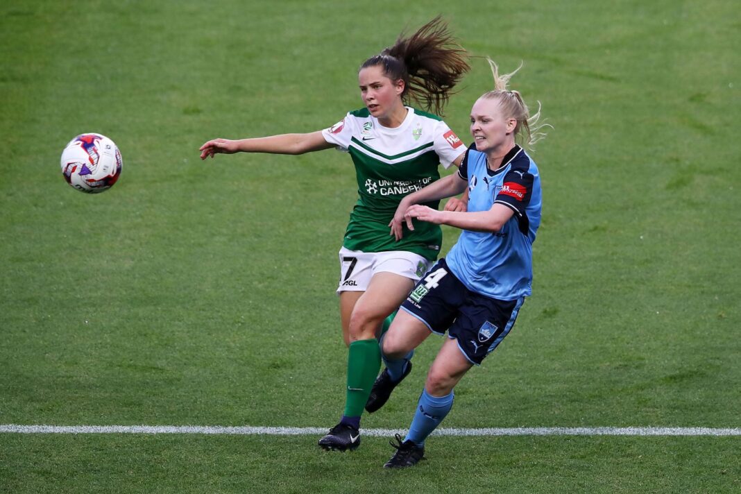 two female soccer players going for the ball