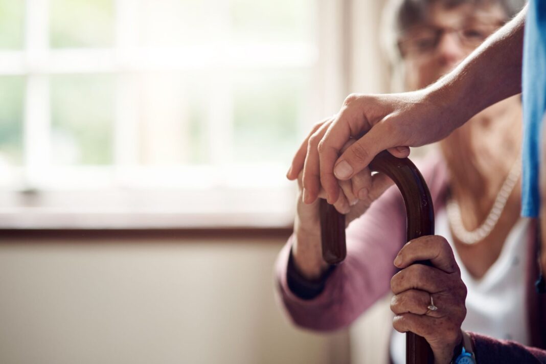 elderly womans hand being touched by her carer