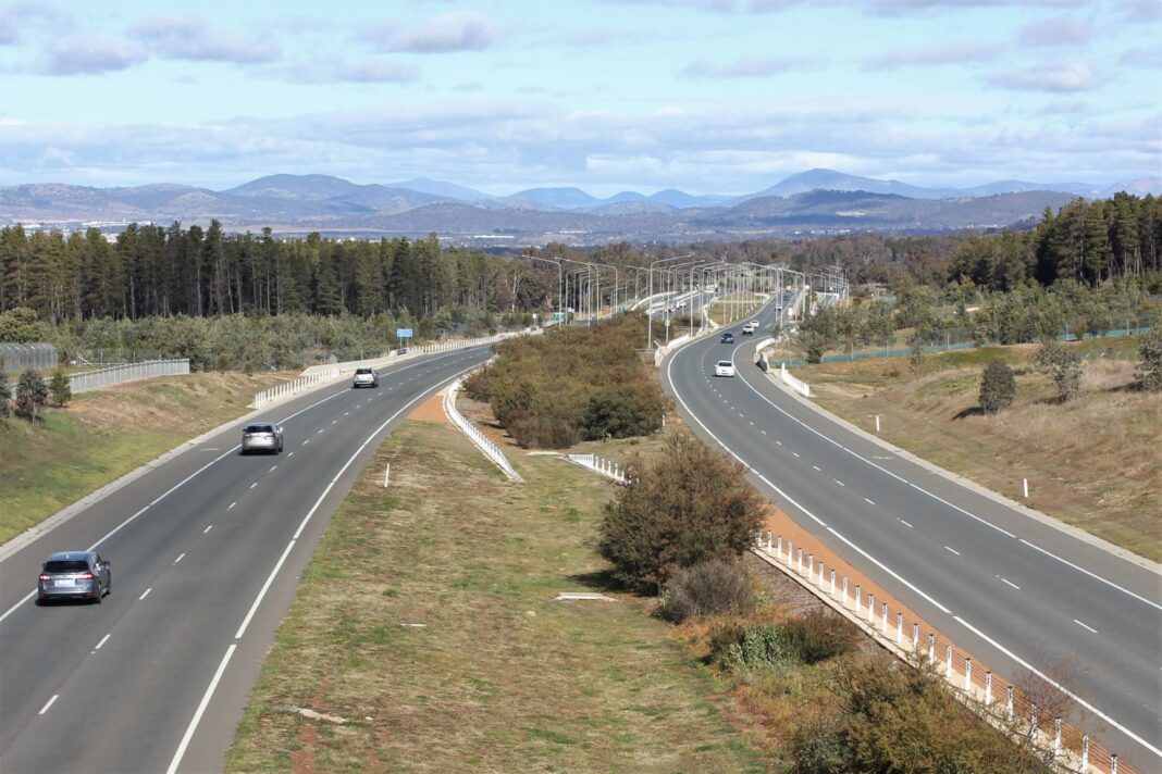 Low volume of traffic driving in both directions along a separated four-lane highway in Canberra
