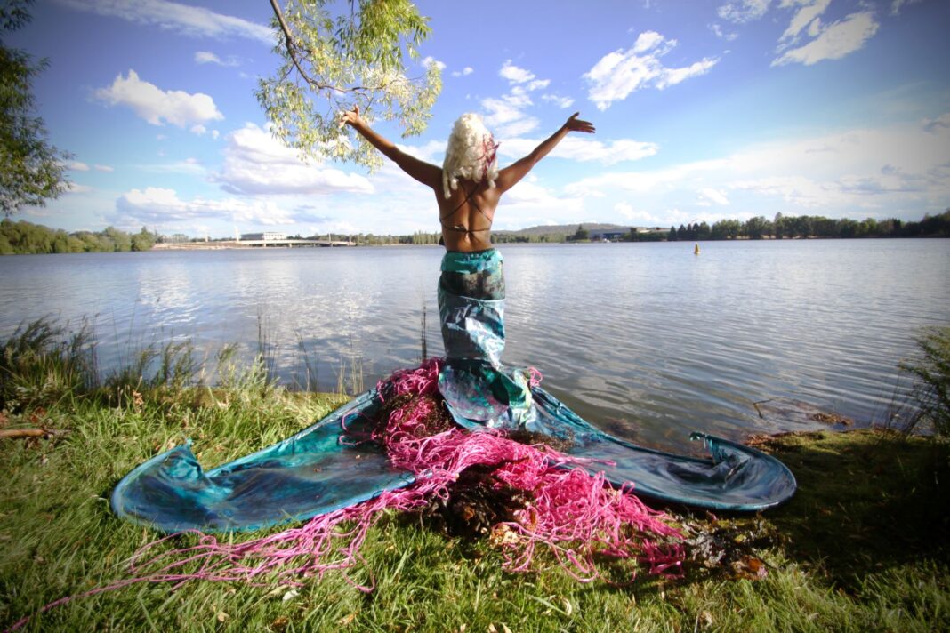 woman dressed as mermaid next to water