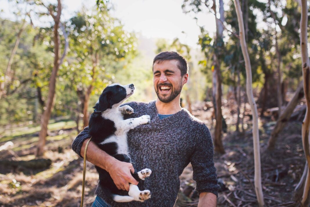 man smiling while holding his dog