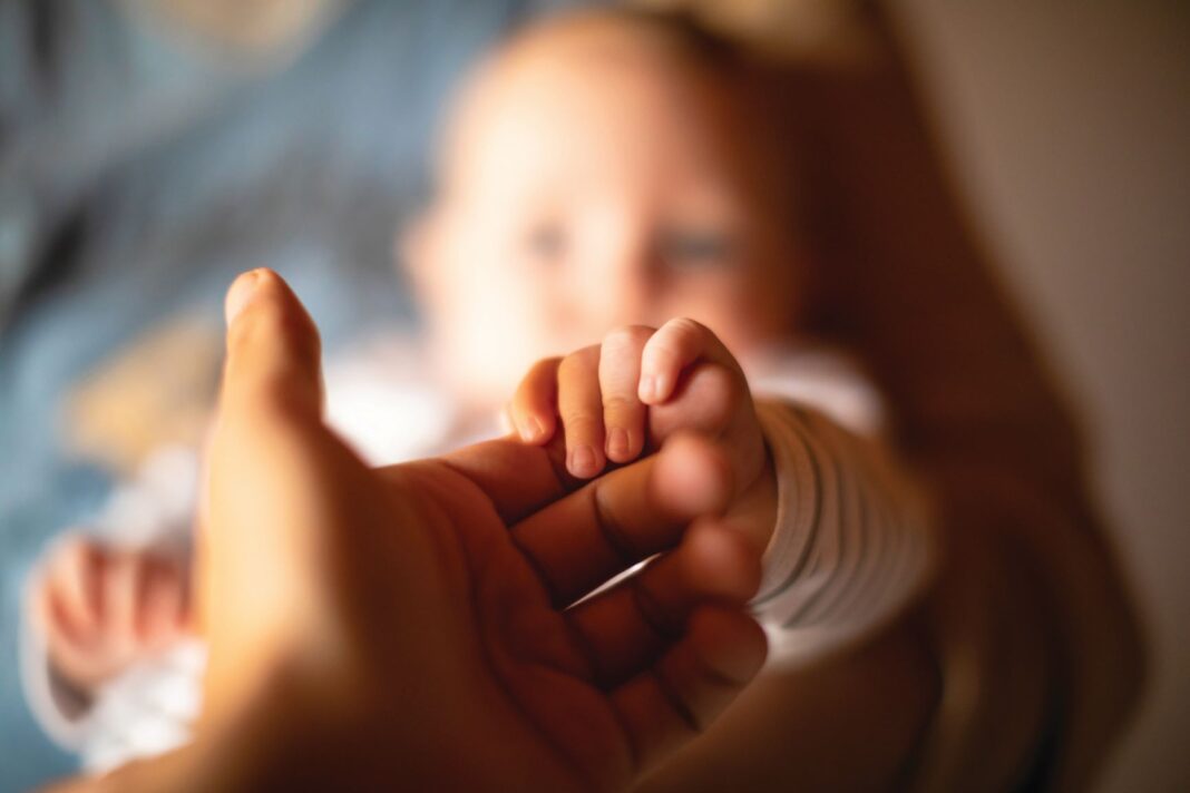 close up of woman holding a babys hand