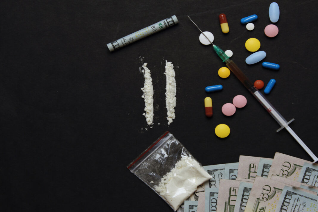 cocaine and drug pills on black background