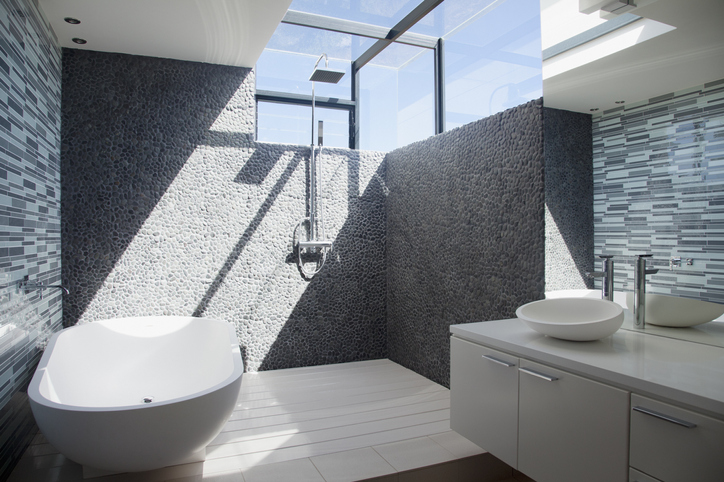 Sunlight streaming into contemporary designer bathroom with grey pebble feature walls