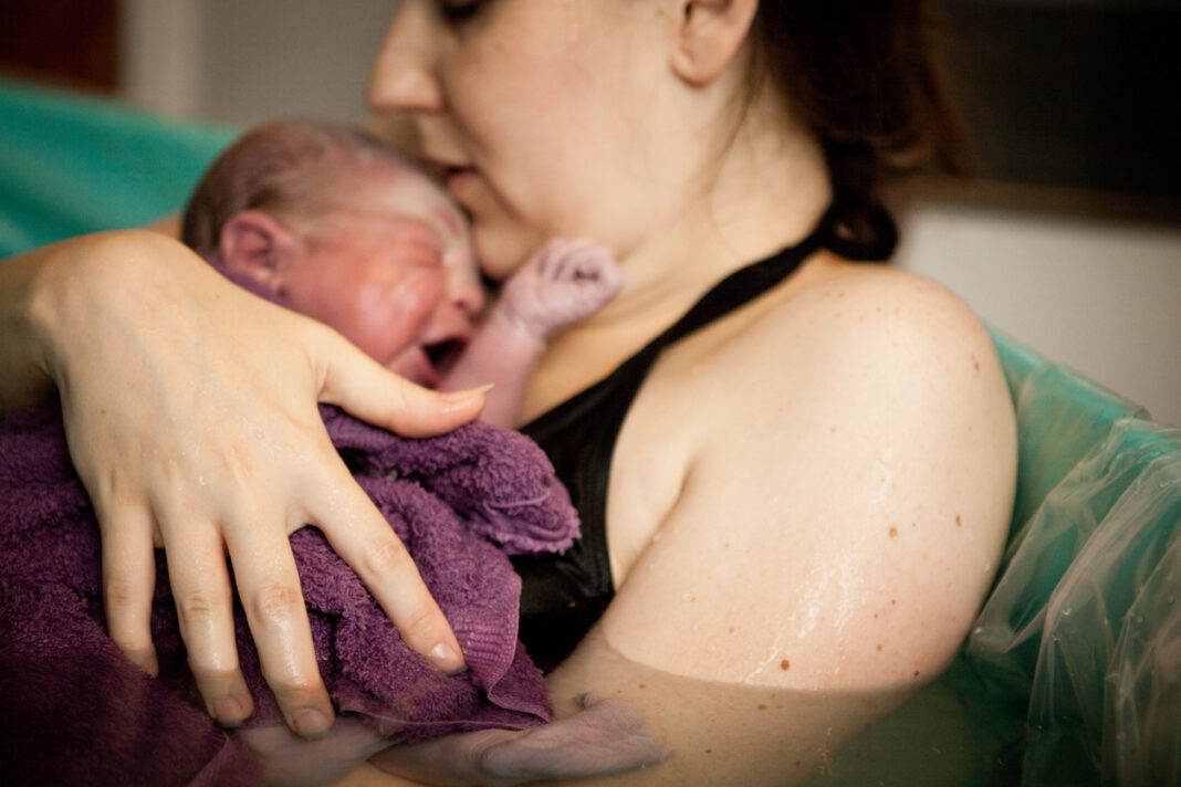 Mother Holding Newborn in Birthing Tub After Home Water Birth