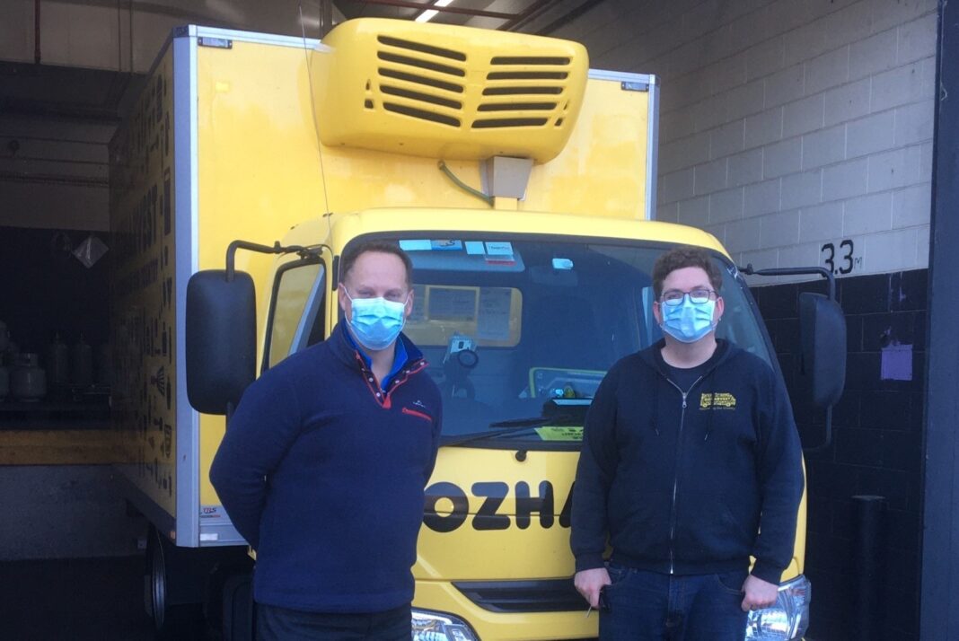 two men with masks on standing at a truck
