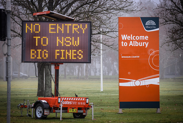 Roadside mobile message board stating: 'No entry to NSW big fines' beside big orange 'Welcome to Albury' sign.