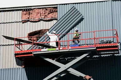 Two men on cherry picker replacing cladding on a building