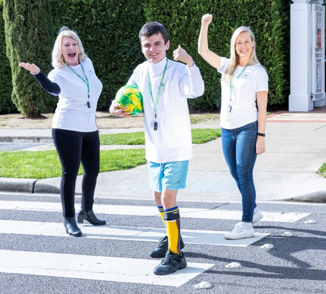 Two smiling women and one teenage boy walking across a zebra crossing in the sunshine