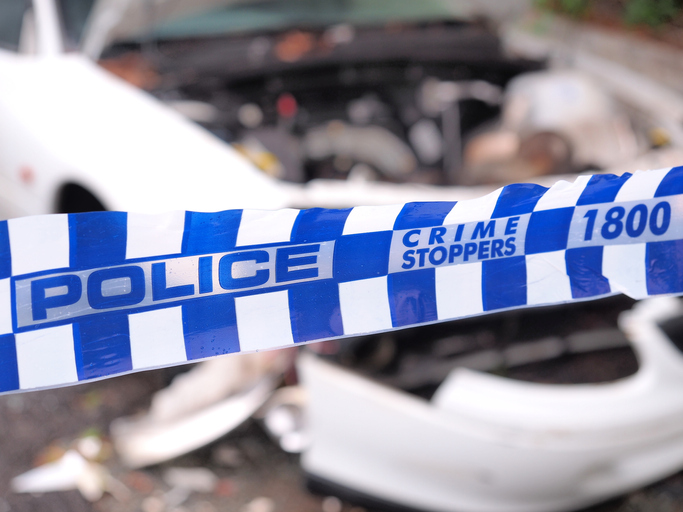 Blue and white Police tape cordoning off a area with a badly accident damaged white car, , Australia 2016