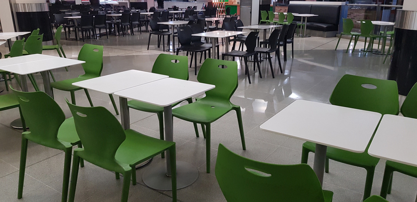 Chairs and tables in a cafeteria food court with no people
