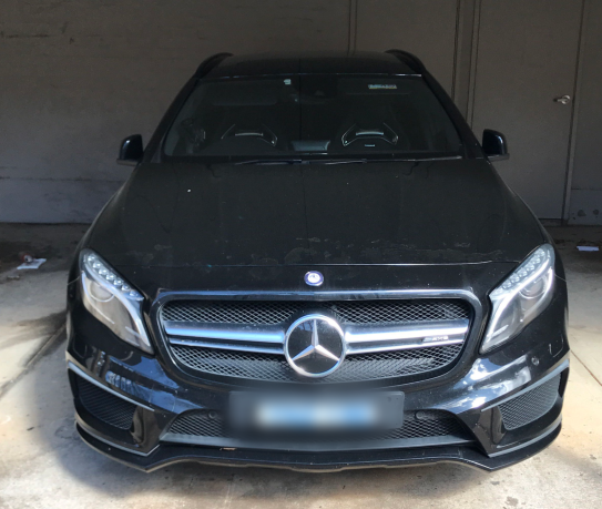 Black Mercedes sedan with number plate pixilated parked in a garage