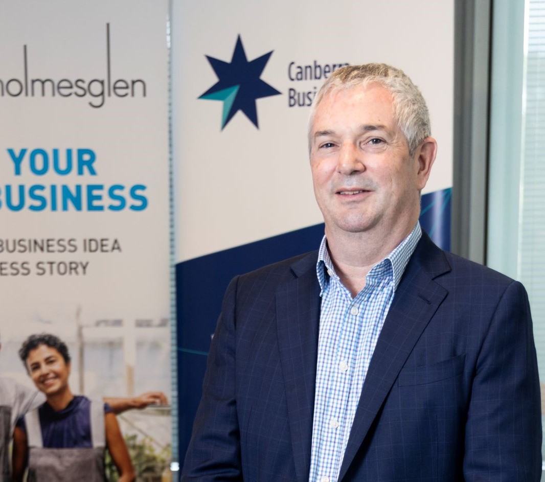 business man in blue suit standing in front of Canberra Business Chamber sign