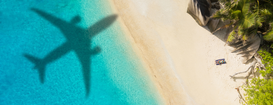 shadow of jet plane over sunny sandy beach with turquoise water