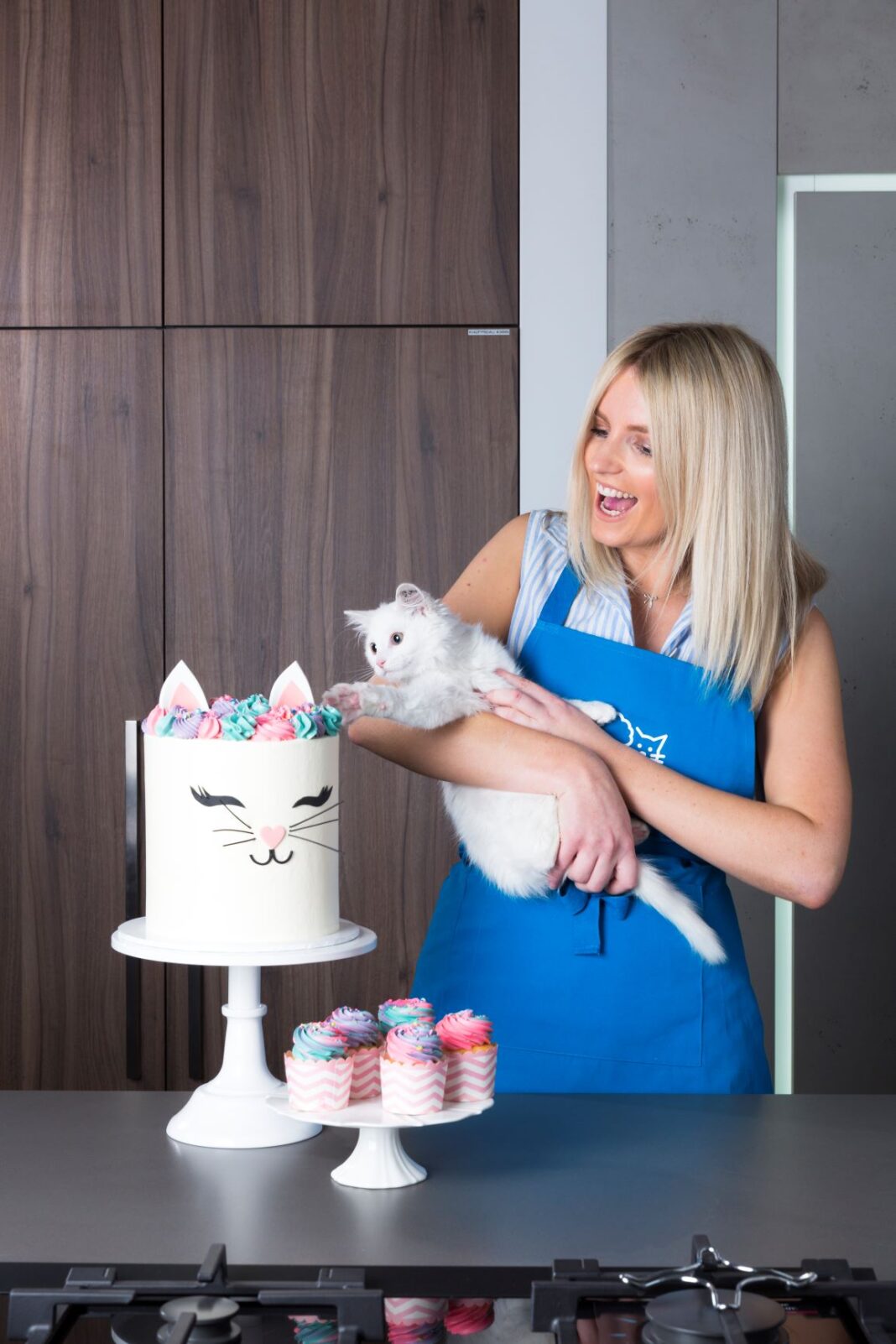 woman holding a cat with a cake nearby