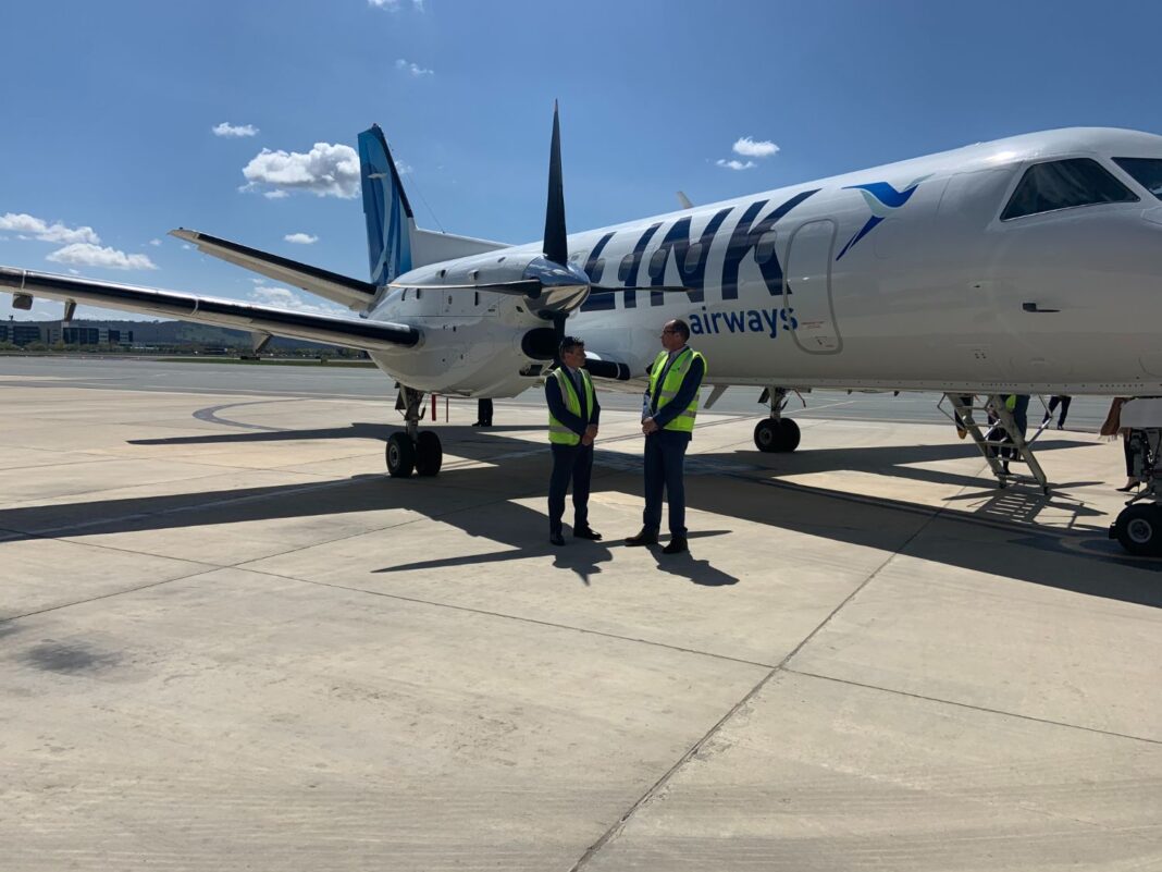 Two men standing on tarmac in front of Link Airways airplane
