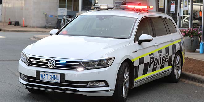 White police car with WATCHNU number plate, parked on the street