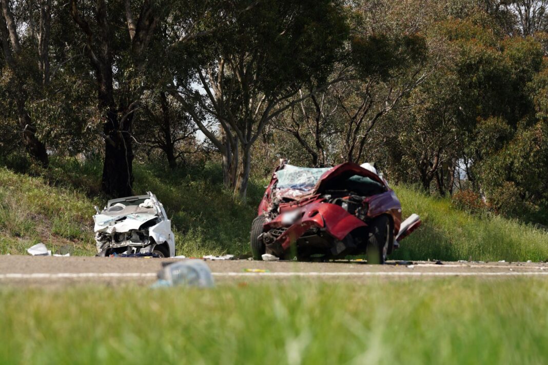 Two crumpled cars, one red and one white, on a road following a serious collision