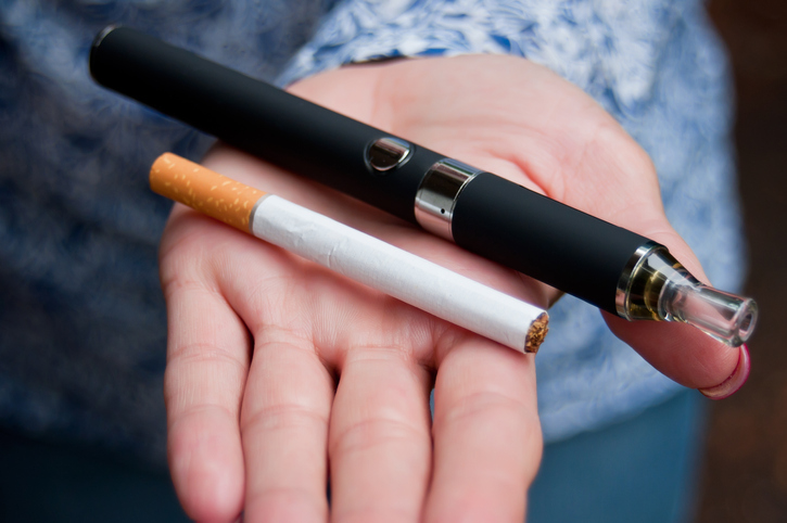 closeup of hand of woman with e-cigarette and cigarette