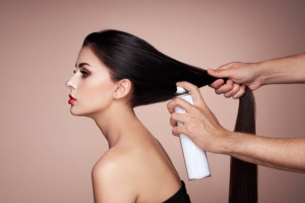 attractive woman getting her hair sprayed with dry shampoo