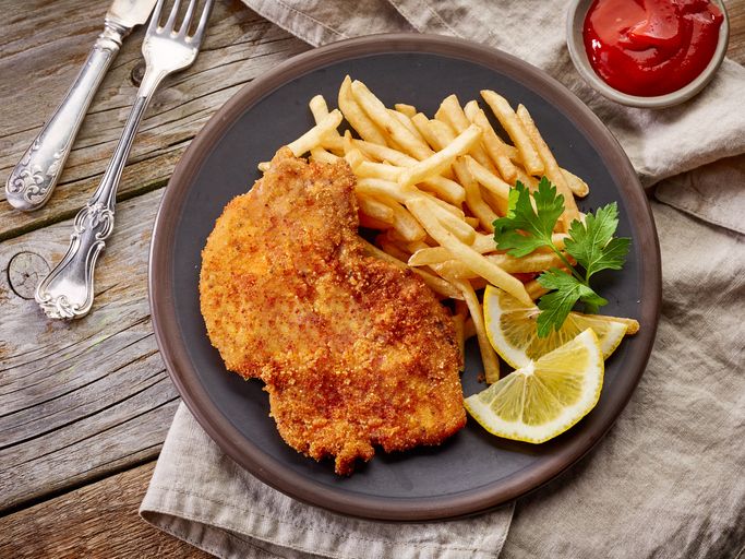 chicken schnitzel with some chips and lemon on a plate