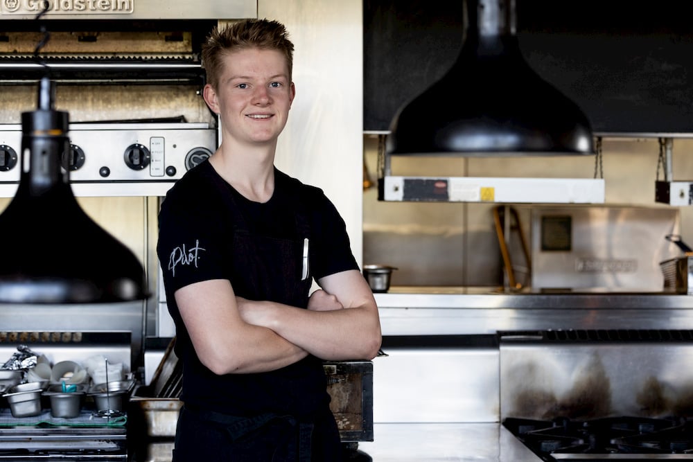 Teenage boy in t-shirt standing in commercial kitchen