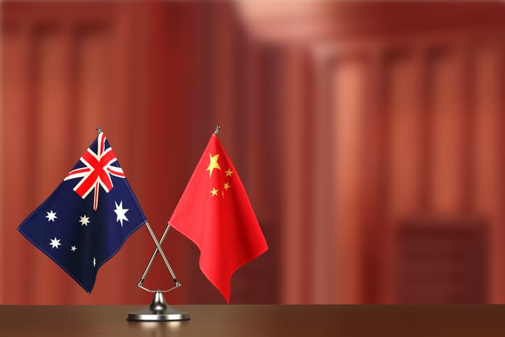 Two crossed national flags of ustralia and China on wooden table
