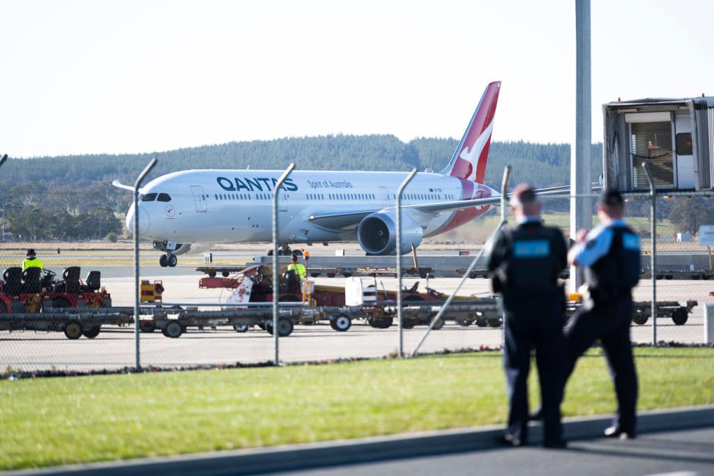 Police watch a repatriation flight from Delhi arrive at Canberra Airport in May. (Photo by Rohan Thomson/Getty Images)