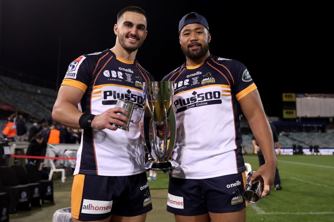 Two, smiling, Brumbies male rugby players holding a trophy