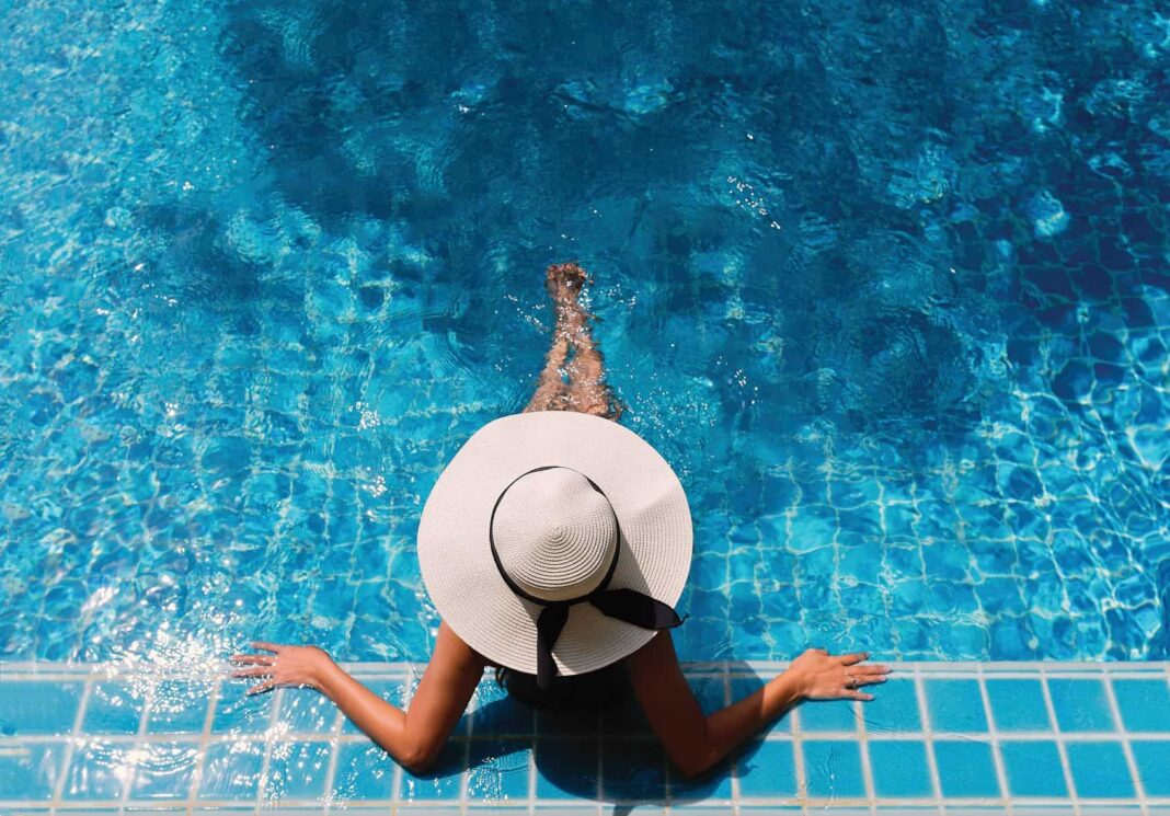 woman lounging in a pool with a hat on
