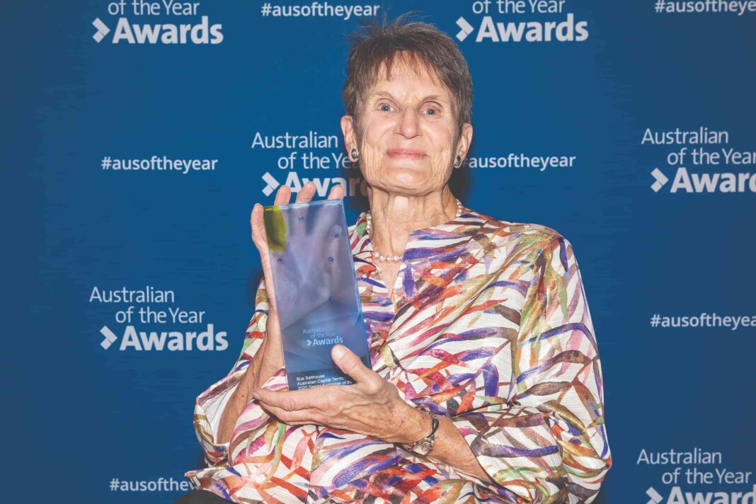 Smiling woman in wheelchair holding ACT Senior Australian of the Year trophy