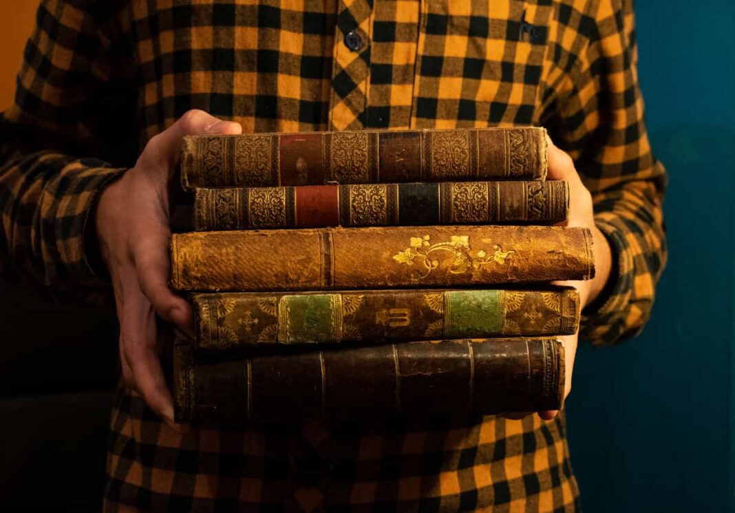 man holding old books