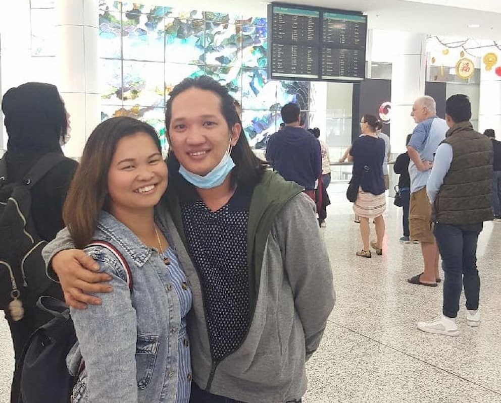 Young Asian man and woman embracing at an airport