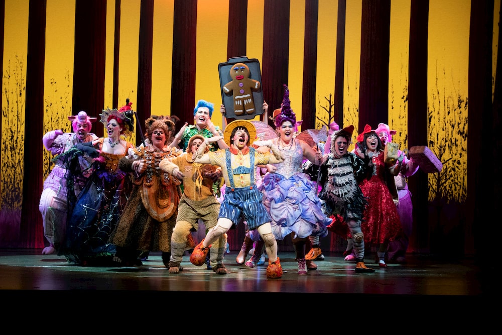 group of around 12 performers on stage in a scene from Shrek the Musical