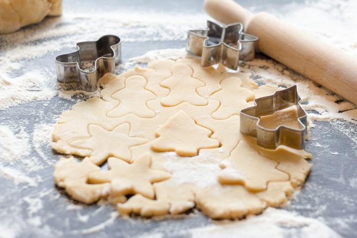 Shortbread dough and cookie cutters on a bench.