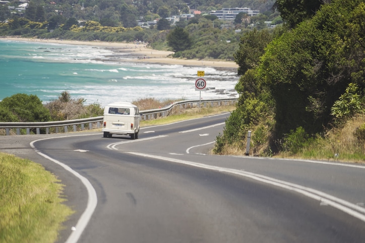 Lorne, Australia - January 3, 2018: A Volkswagen Kombi (or Transporter) van driving down Great Ocean Road, with Lorne Beach in the background.