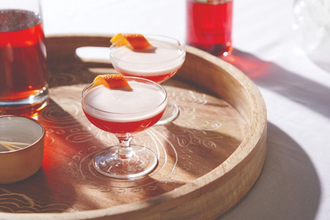 two red cocktails in glasses on a wooden tray