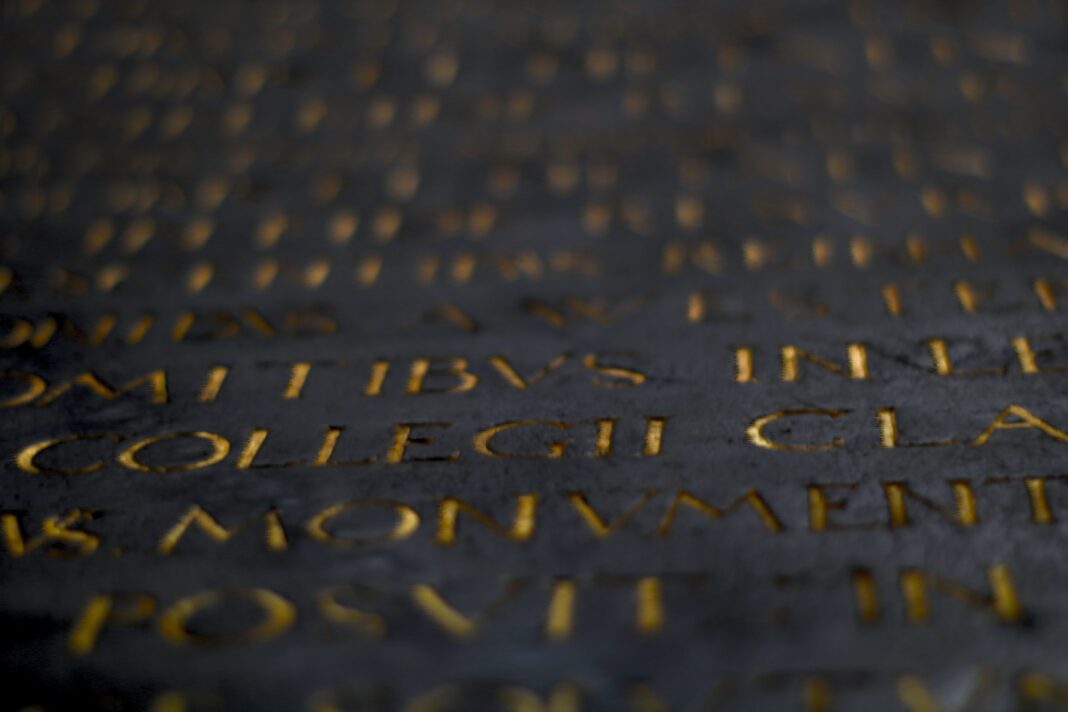 An image of golden roman letters on a black plate to symbolise the new Word of the Decade.